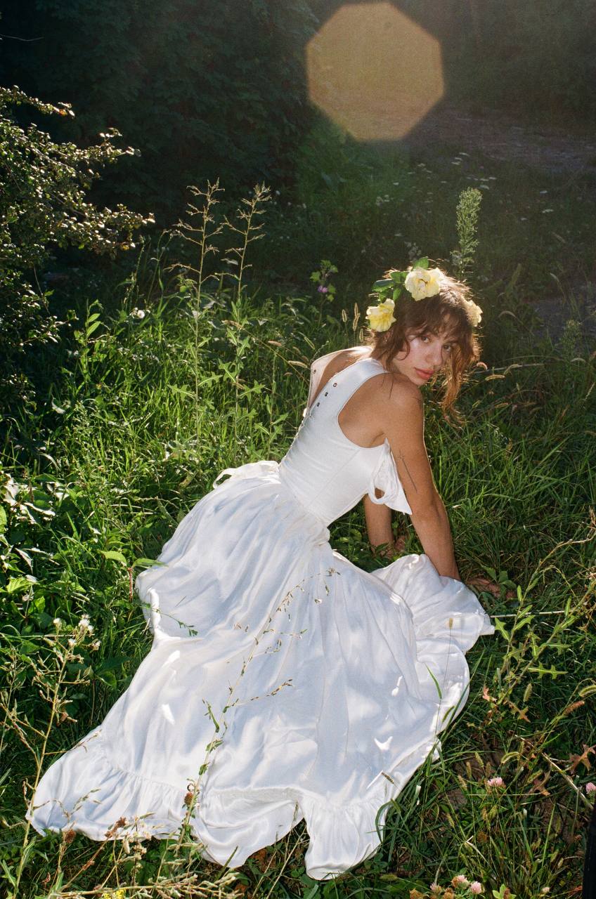 Front view of a princess satin dress with a structured corset bodice and tie-up shoulder bows.