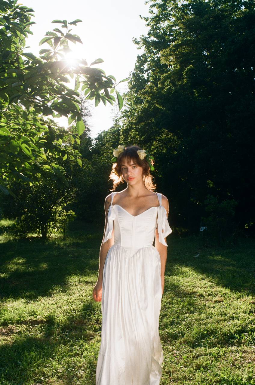 Front view of a princess satin dress with a structured corset bodice and tie-up shoulder bows.